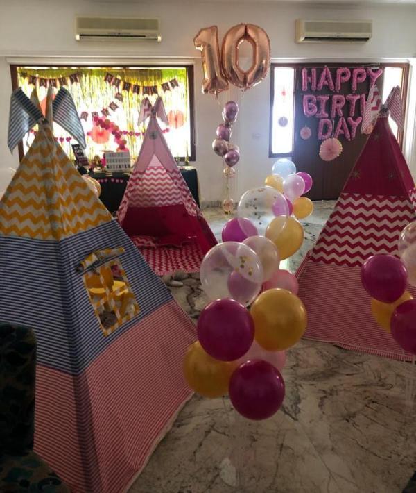 A slumber birthday party for kids set up with 3 teepee tents and baloons
