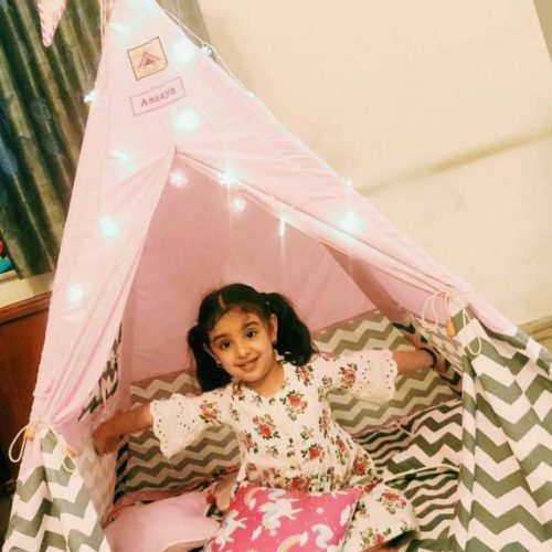 a girl enjoying camping in a pink tent house for kids