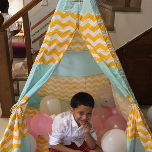 a boy sitting in his green and yellow play tent